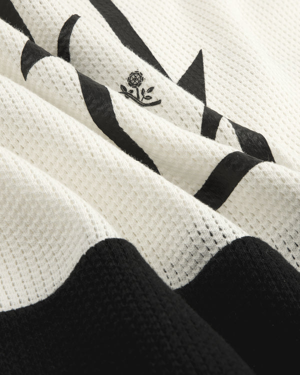 Close-up of the Long-Sleeve Mesh Enduro Tee, featuring white mesh with a black abstract design and small flower emblem.