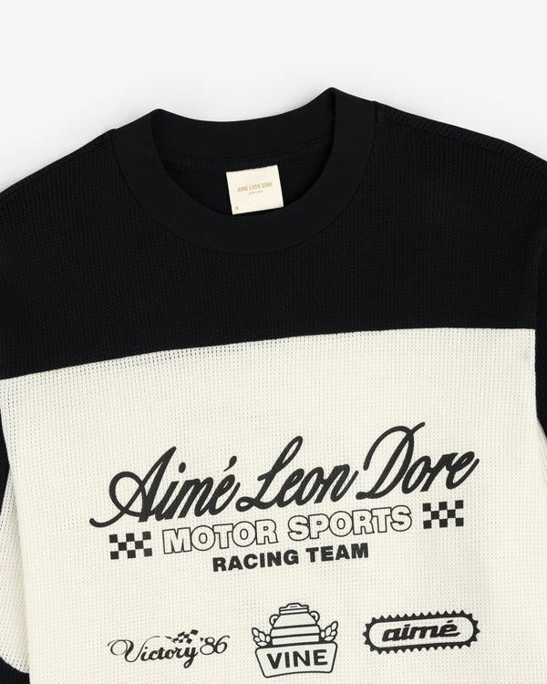 Black and white Long-Sleeve Mesh Enduro Tee by Aimé Leon Dore with racing-themed front text and logos.