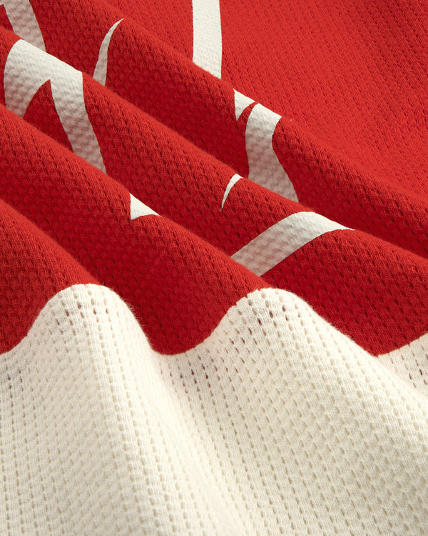 Close-up of the Long-Sleeve Mesh Enduro Tee’s red and white wavy pattern and visible mesh fabric texture.