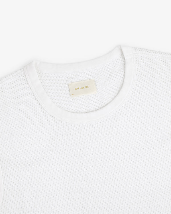 A close-up of a white Mesh Muscle Tank with a beige label inside the collar.