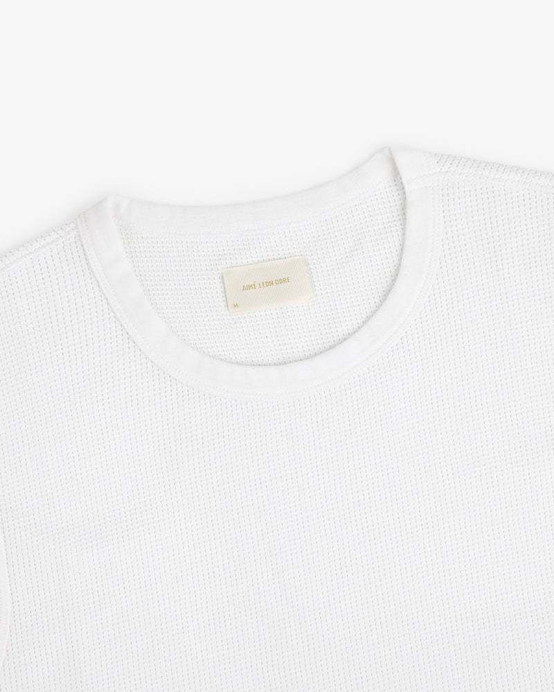 A close-up of a white Mesh Muscle Tank with a beige label inside the collar.