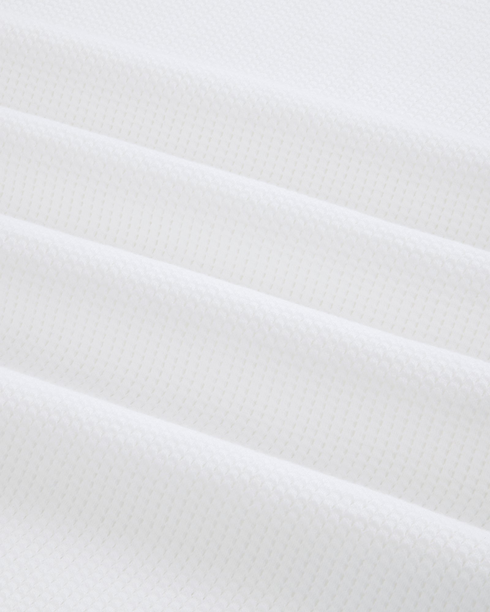 Close-up of folded white Mesh Muscle Tank fabric with a subtle geometric pattern and soft, even lighting.