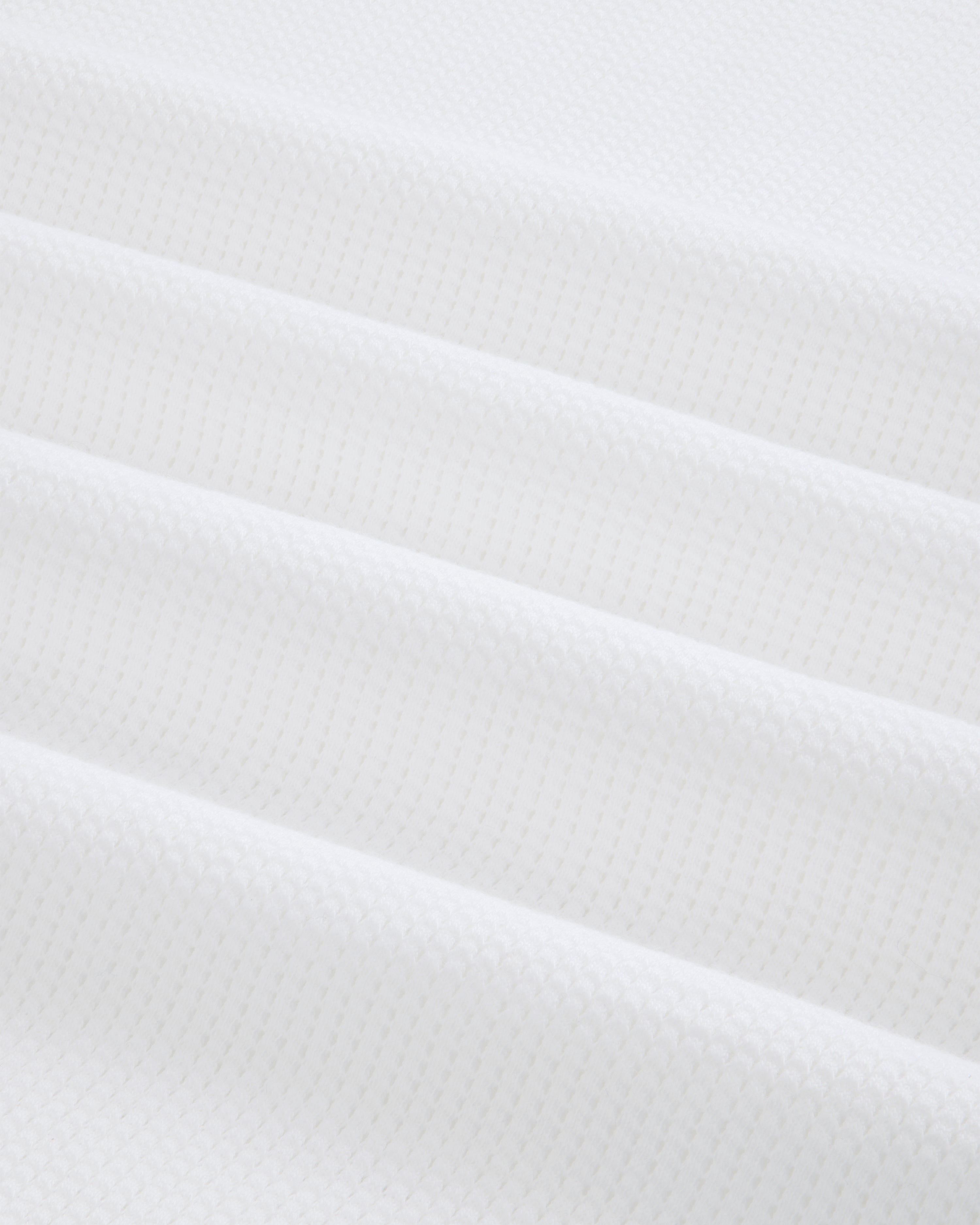 Close-up of folded white Mesh Muscle Tank fabric with a subtle geometric pattern and soft, even lighting.