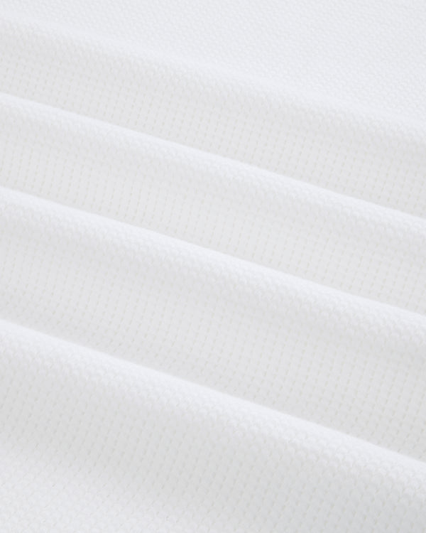 Close-up of folded white Mesh Muscle Tank fabric with a subtle geometric pattern and soft, even lighting.