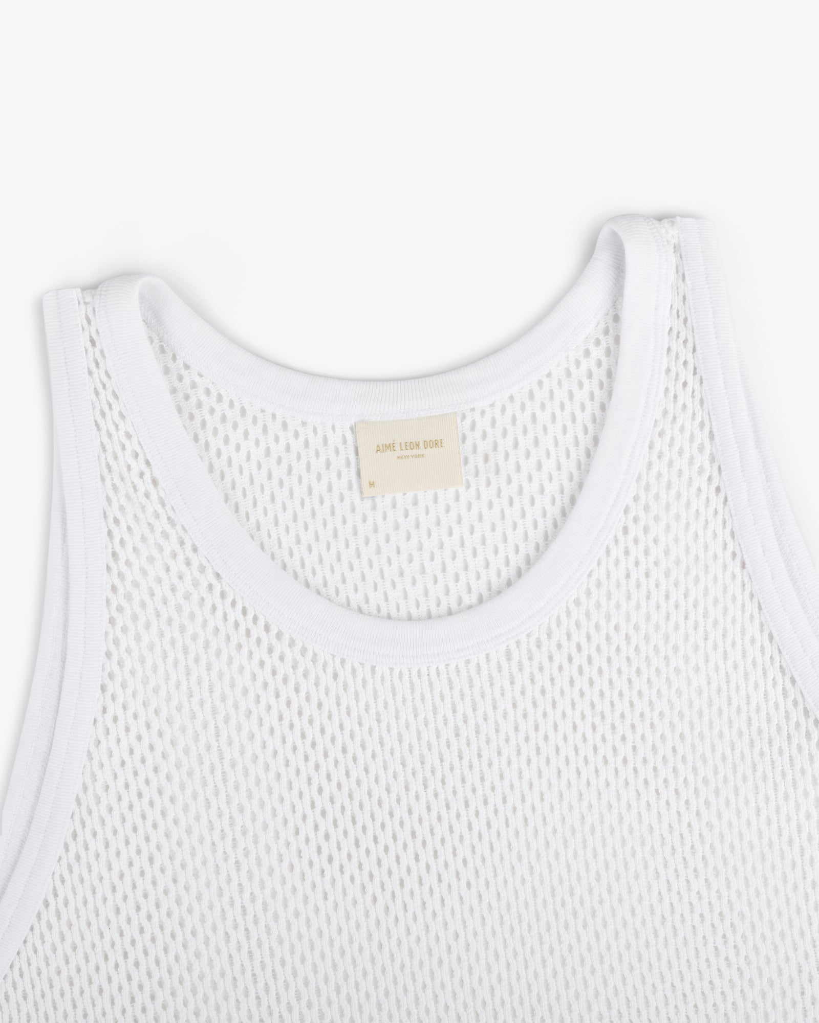 Close-up of Mesh Tank Top in white with ribbed edges and a beige neck label, shown on a white background.