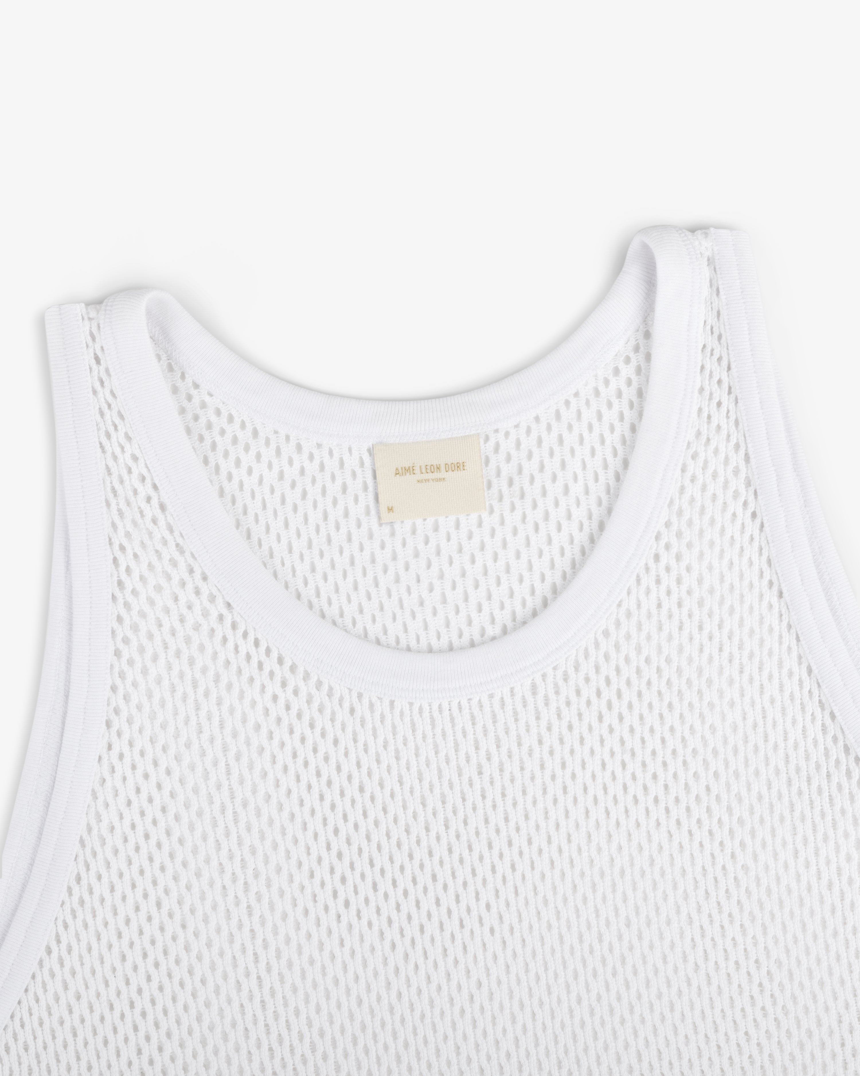 Close-up of Mesh Tank Top in white with ribbed edges and a beige neck label, shown on a white background.