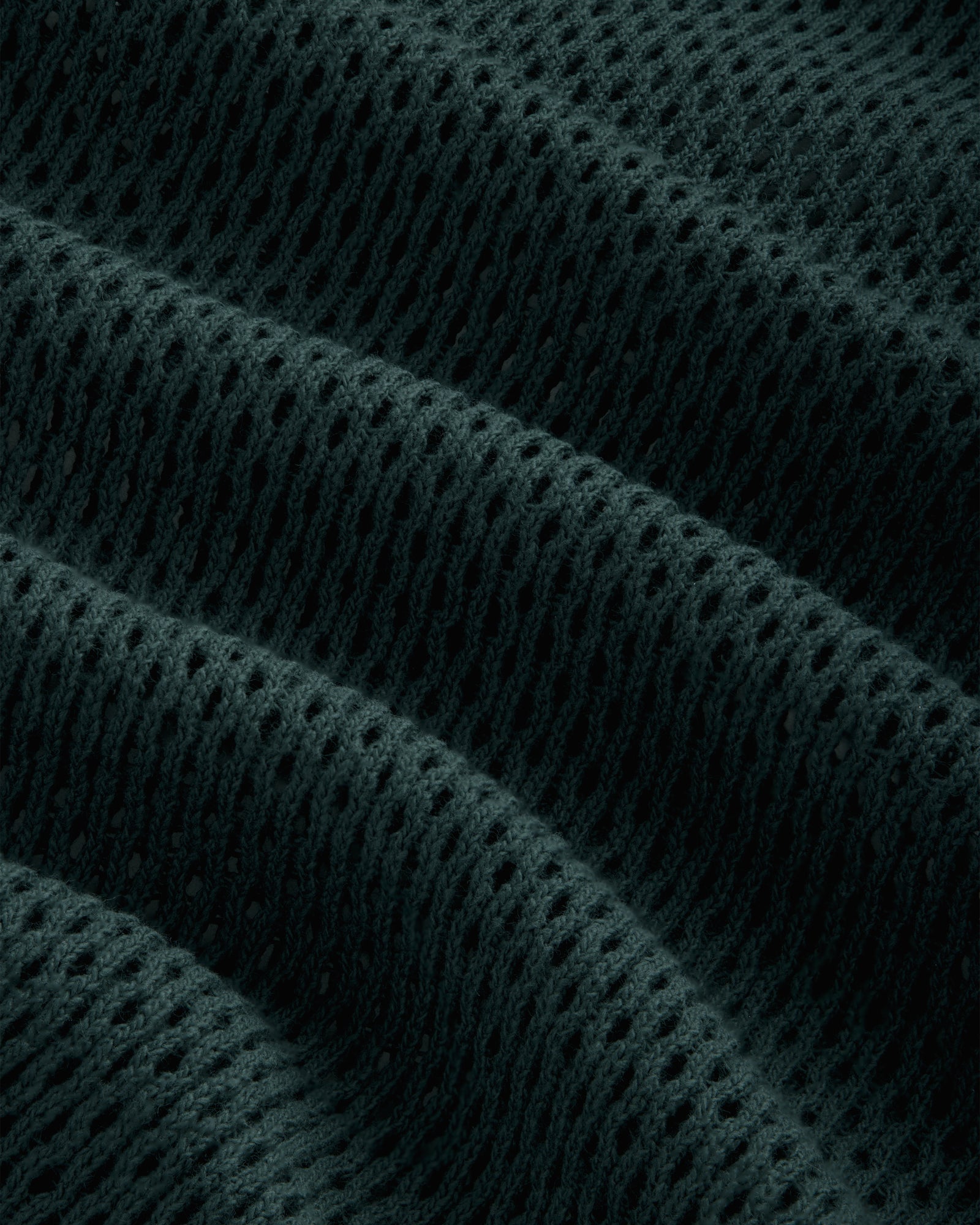 Close-up of Mesh Tank Top fabric featuring dark, textured mesh with raised wavy ridges and small, even holes.