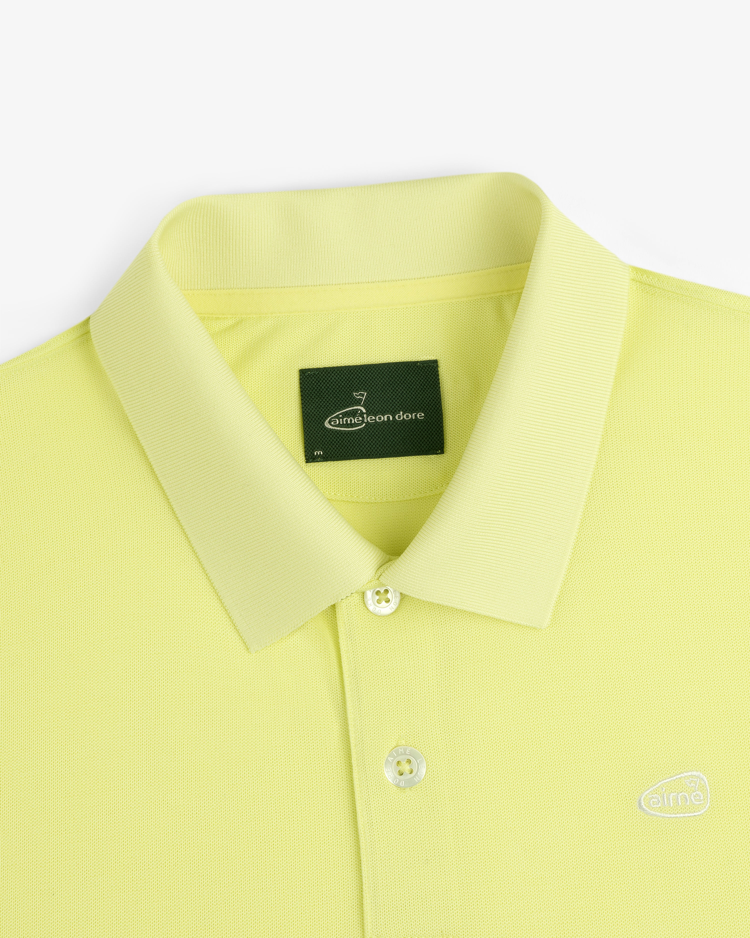 ALD Golf Polo: Yellow collared shirt with buttons, green neck label, and small embroidered logo.