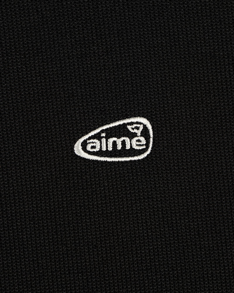 Black textured ALD Golf Polo with small white "aime" logo embroidered inside an irregular oval.
