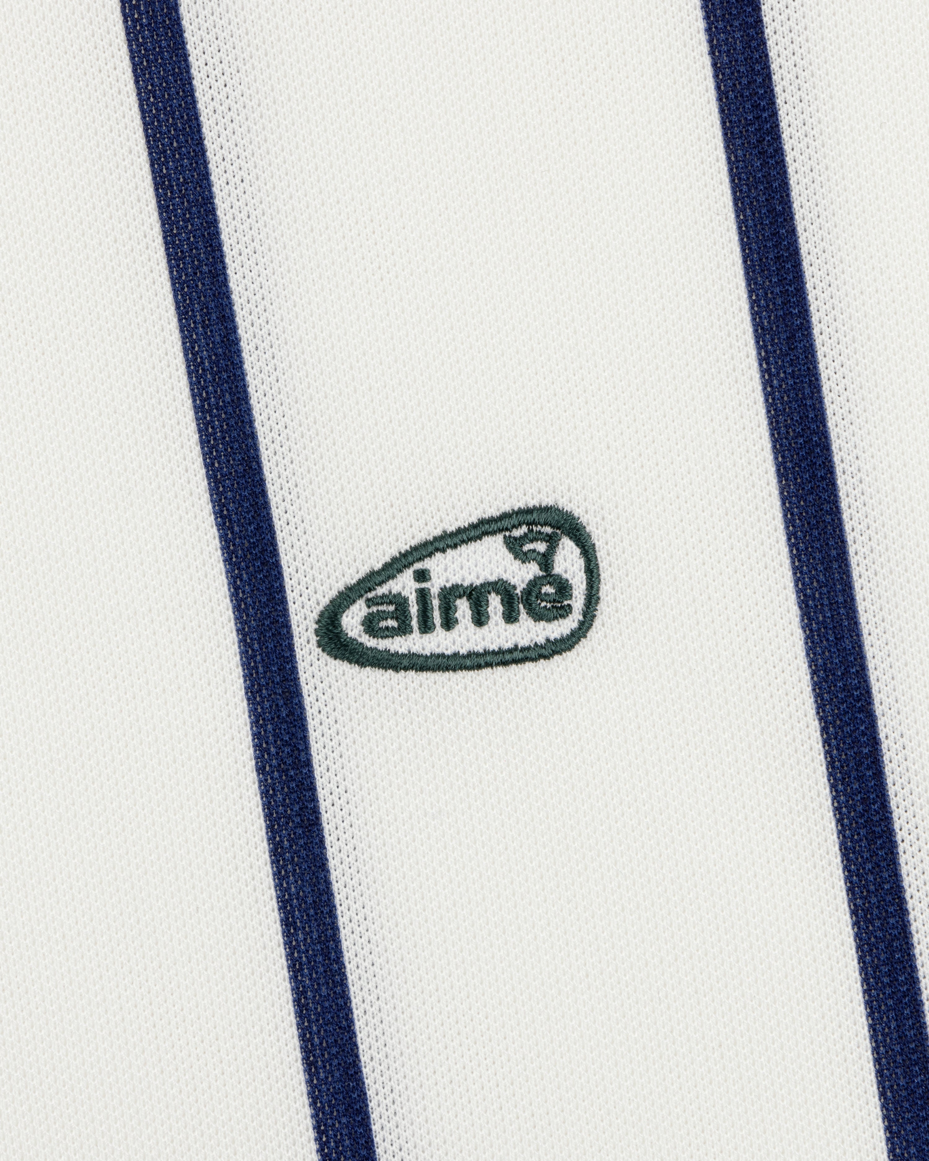 The ALD Golf Polo features white fabric with vertical navy stripes and a small green aimé logo embroidered at the center.