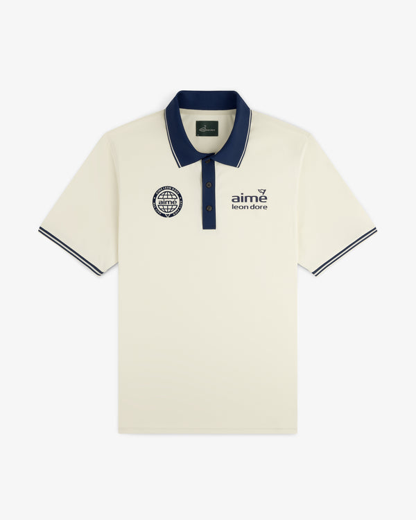 ALD Golf Tour Polo in cream with dark blue collar, sleeve trim, and chest logos, laid flat on white background.