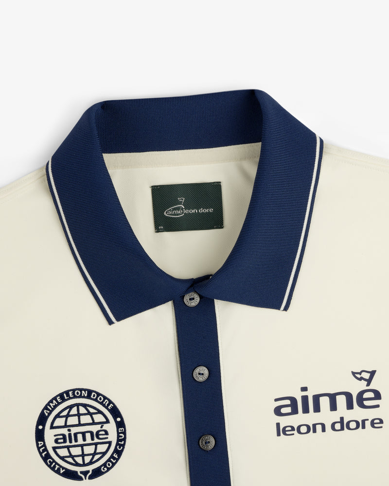 ALD Golf Tour Polo: Cream shirt with navy collar, logo, and “All City Golf Club” globe emblem on the chest.