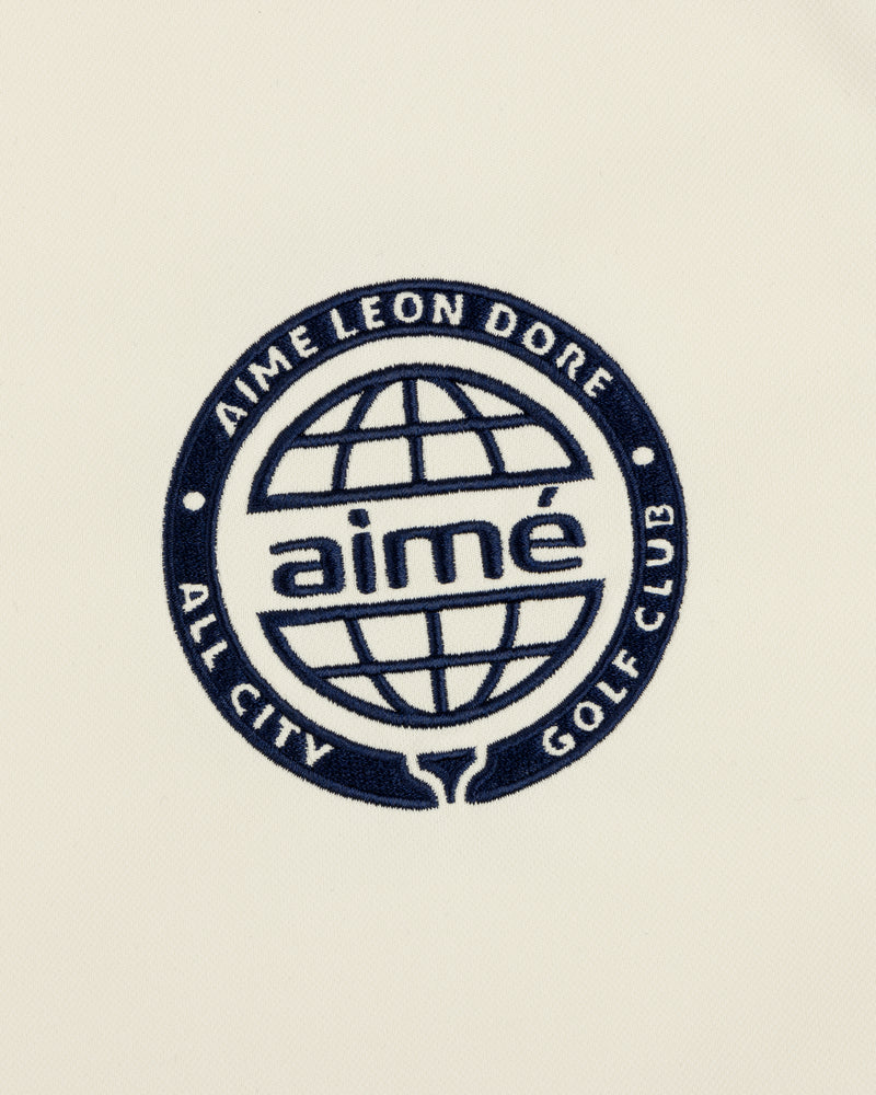 Navy blue ALD Golf Tour Polo with All City Golf Club globe logo and "aimé" on a cream background.