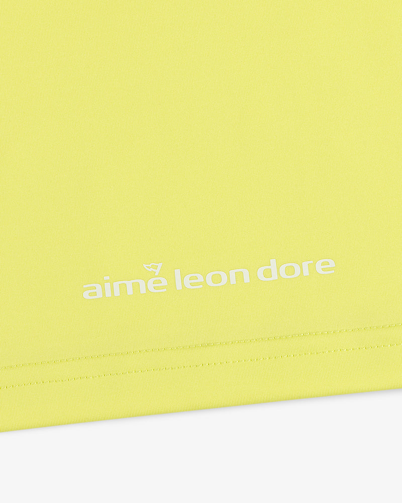 Close-up of the ALD Golf Performance Tee in yellow with the aime leon dore logo printed in white near the hem.