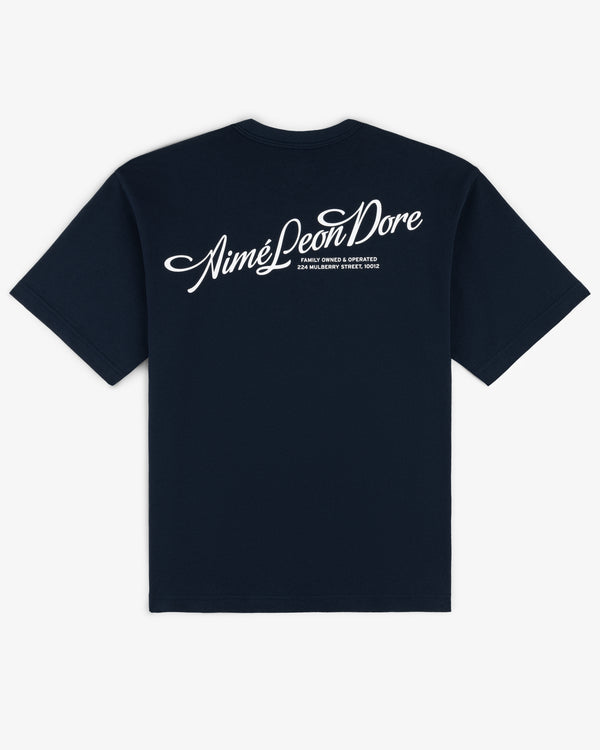 Navy blue Pappoús Logo Tee by Aimé Leon Dore with small white script text on the upper back.