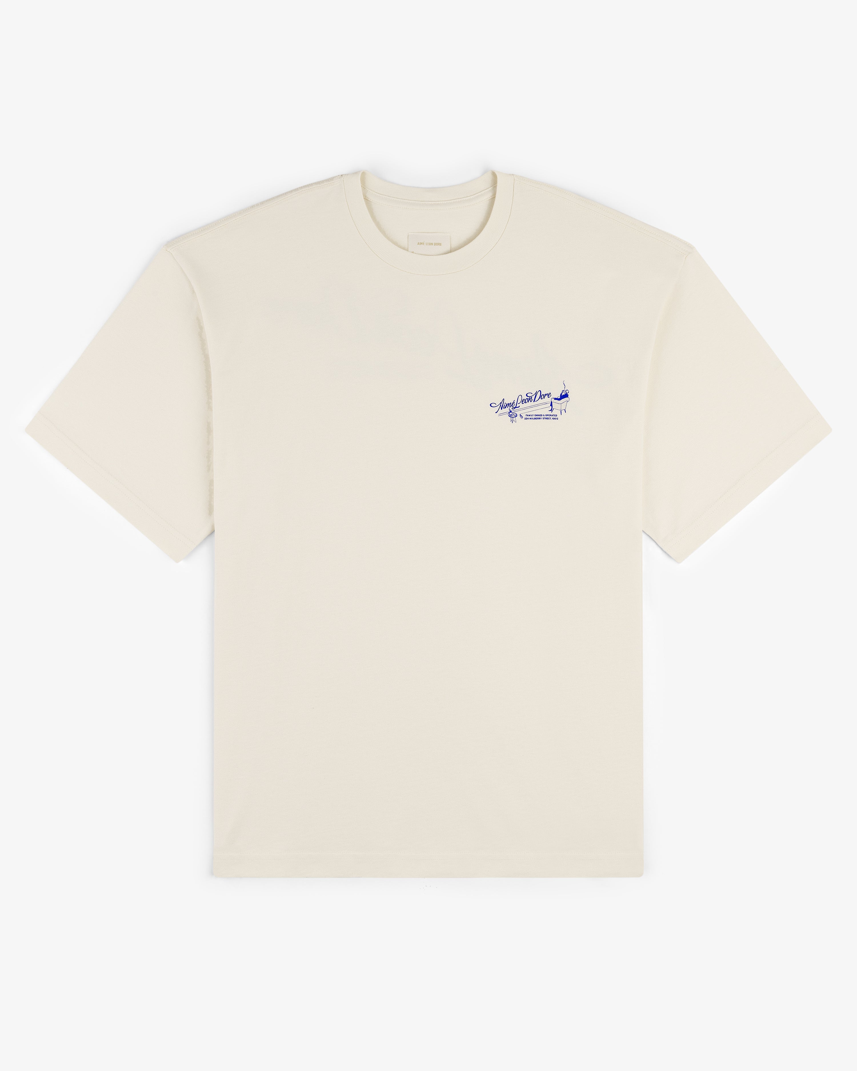 Pappoús Logo Tee: Off-white short-sleeve shirt with small blue script and airplane graphic on left chest.