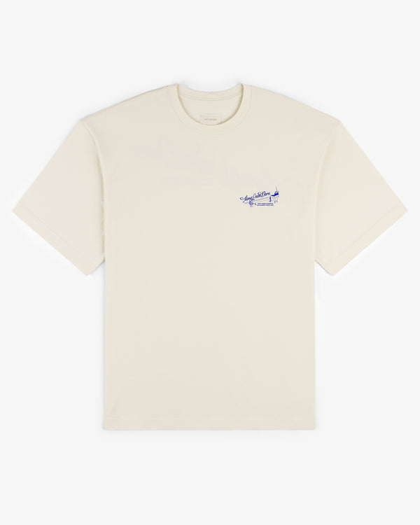 Pappoús Logo Tee: Off-white short-sleeve shirt with small blue script and airplane graphic on left chest.