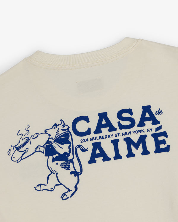 Long-Sleeve Casa Tee: Cream shirt with blue bull holding bread and "CASA de AIMÉ, 224 Mulberry St. New York, NY.