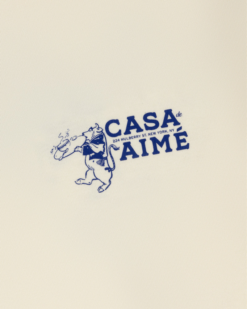 A cartoon bear in a scarf with bread beside "Long-Sleeve Casa Tee, 324 Mulberry St. New York, NY" in blue.