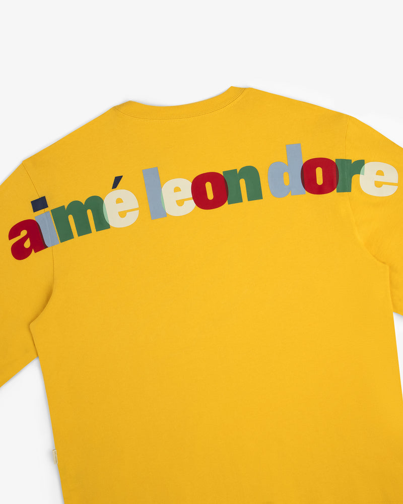 Long-Sleeve Souvenir Tee: Yellow shirt with "aimé leon dore" in bold, colorful letters across the upper back.