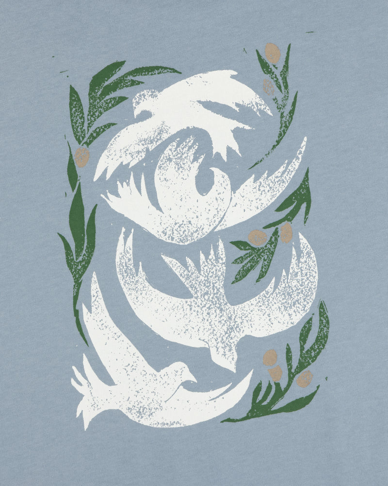 Three white doves soar among leaves and berries on a light blue Woodblock Dove Tee.