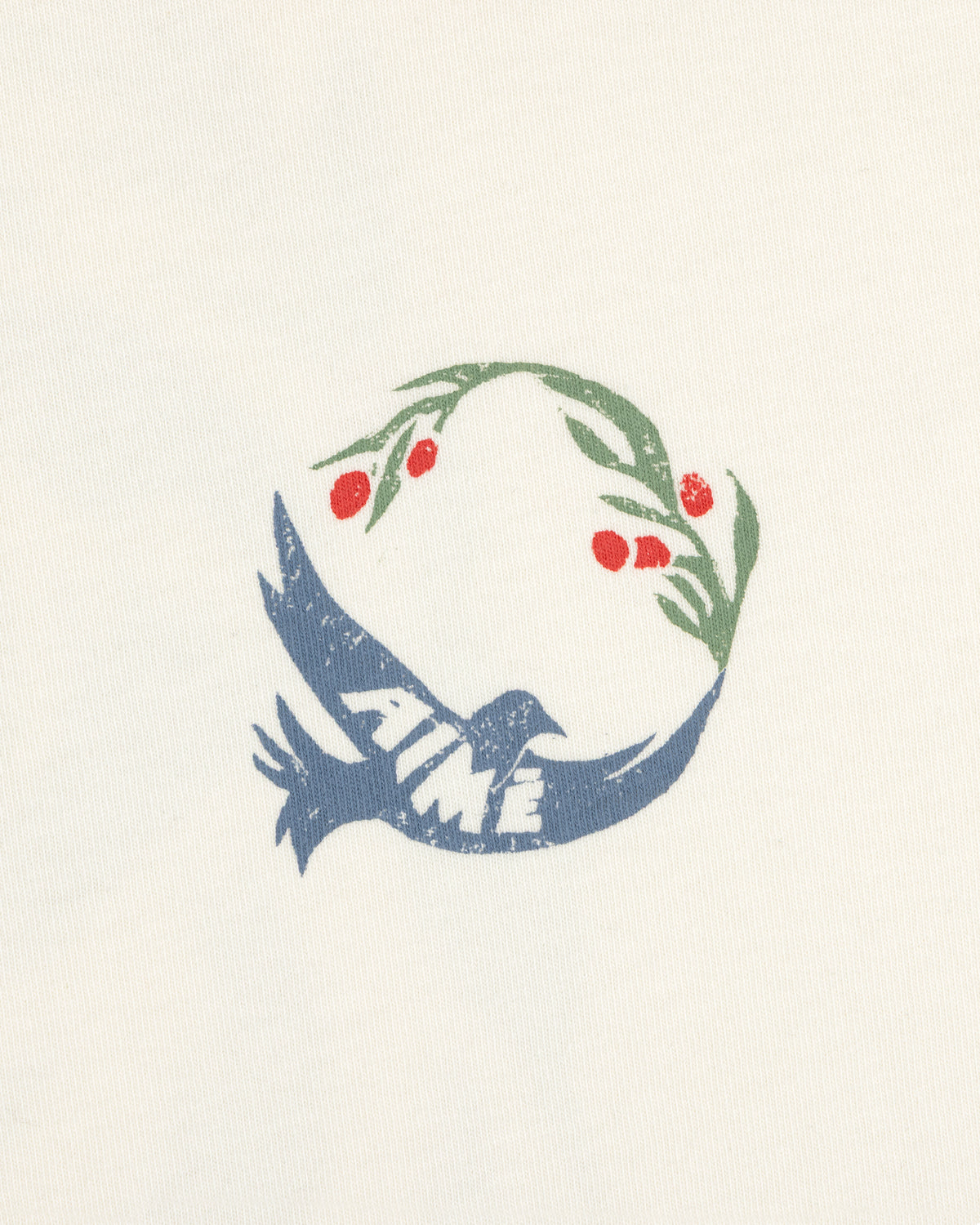 The Woodblock Dove Tee features a blue bird with AIME text, holding an olive branch with red berries in its beak.