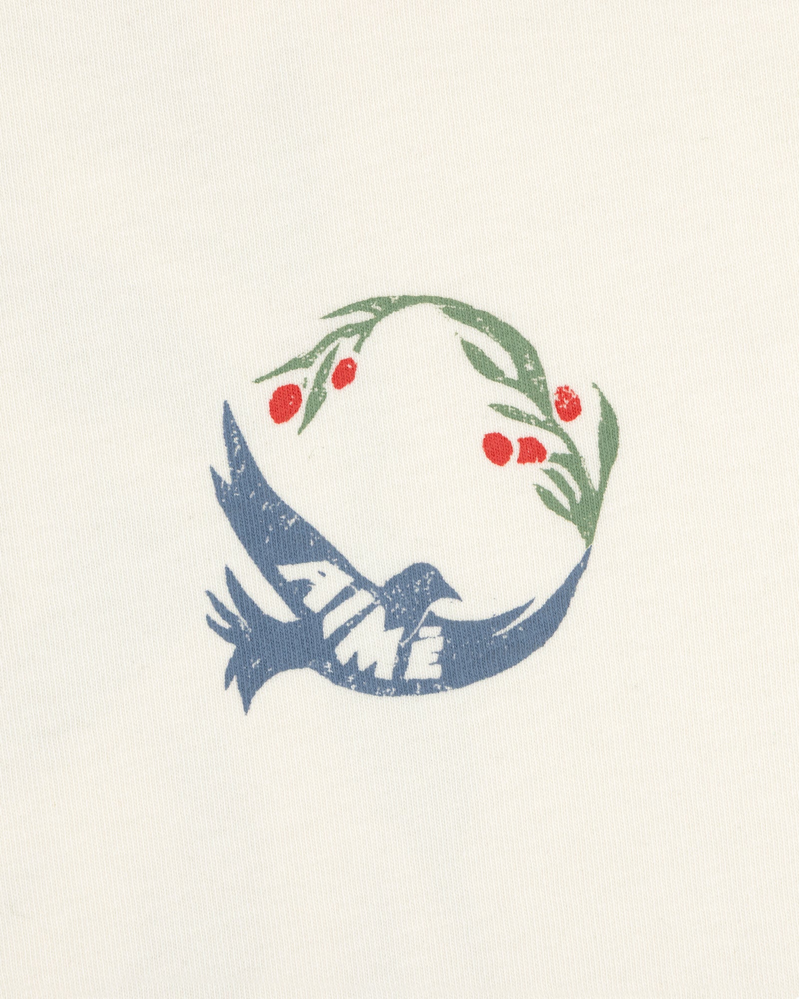 The Woodblock Dove Tee features a blue bird with AIME text, holding an olive branch with red berries in its beak.