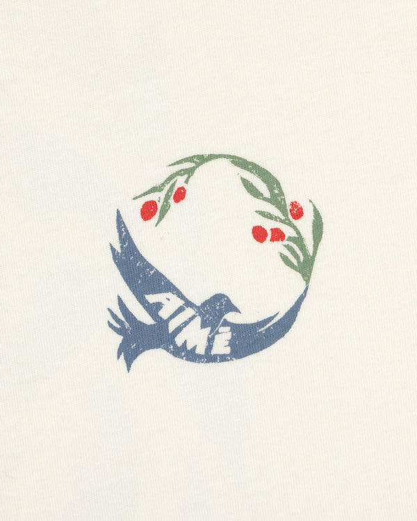 The Woodblock Dove Tee features a blue bird with AIME text, holding an olive branch with red berries in its beak.