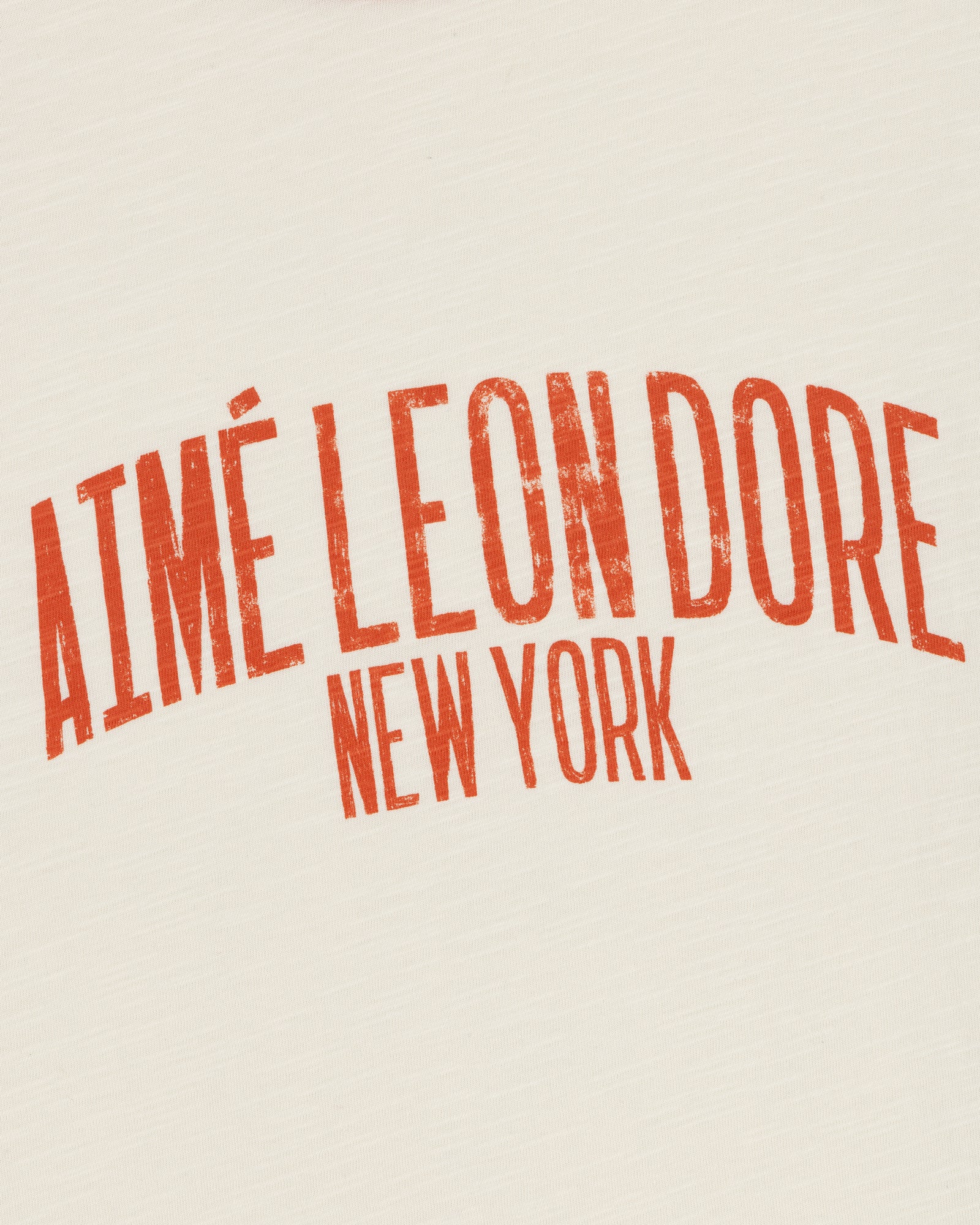 Cream-colored Washed Ringer Tee with bold, red, distressed AIMÉ LEON DORE NEW YORK print.