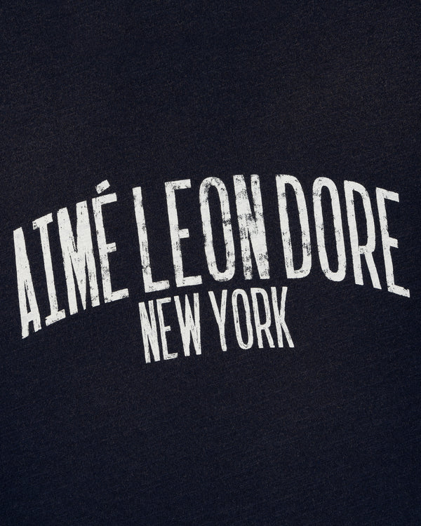 White, distressed "AIMÉ LEON DORE NEW YORK" text on the Washed Ringer Tee's dark fabric background.