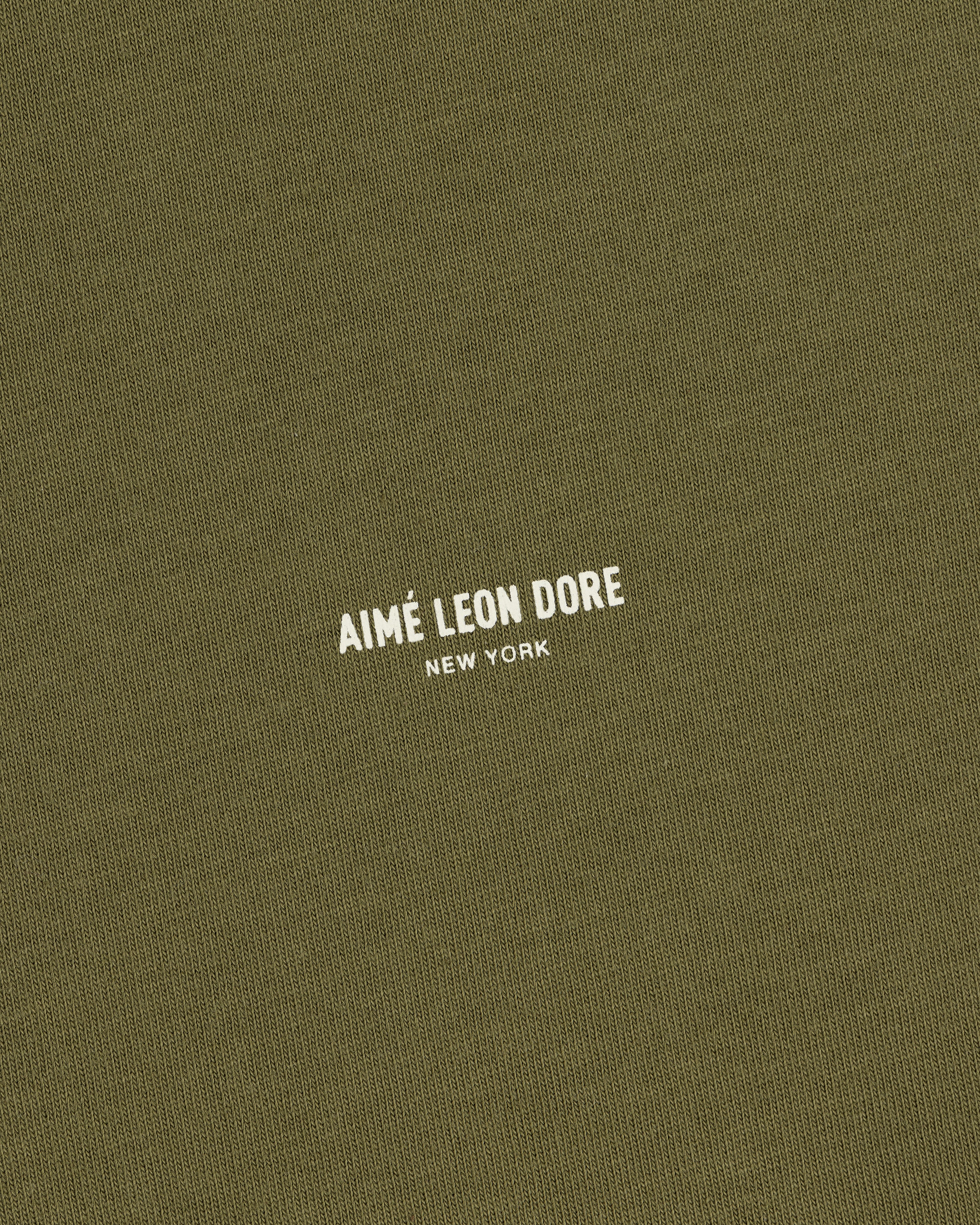 Olive green Safari Tee with small white AIMÉ LEON DORE NEW YORK text printed in the center.