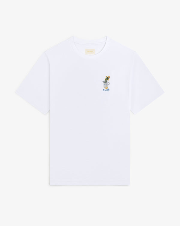 Breakfast Tee: White T-shirt featuring a small embroidered drink graphic and the word "drink" on the upper left chest.