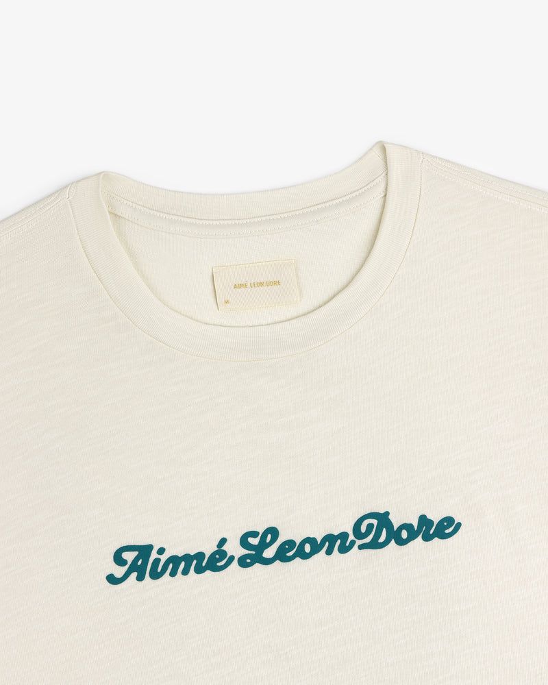 Cream Puff Print Slub Logo Tee with Aimé Leon Dore in green script across the chest.