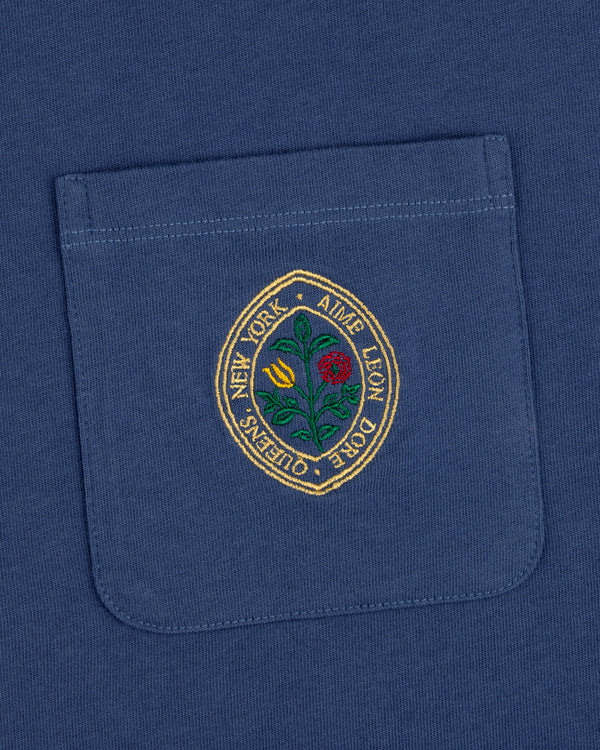 Botanical Crest Pocket Tee: blue shirt pocket with a circular floral patch and "New York - Ames Leon Dore - Queens.