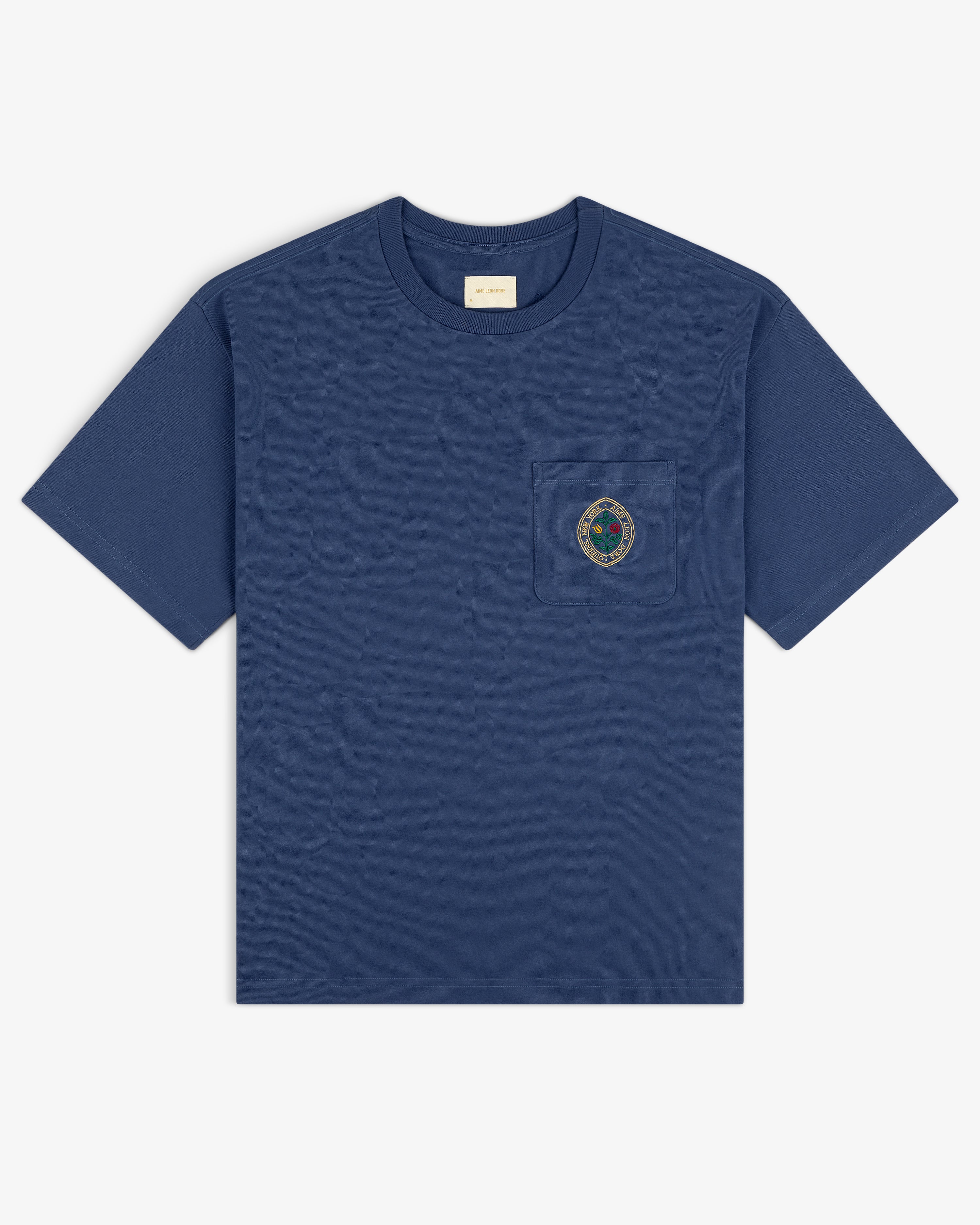 Botanical Crest Pocket Tee—navy blue short-sleeve shirt with chest pocket and circular embroidered crest.
