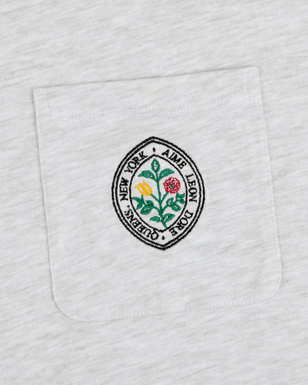 White pocket tee with round floral patch and text: Botanical Crest Pocket Tee by Aime Leon Dore New York Queens.
