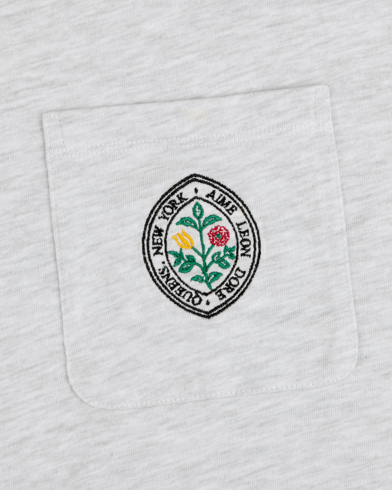 White pocket tee with round floral patch and text: Botanical Crest Pocket Tee by Aime Leon Dore New York Queens.