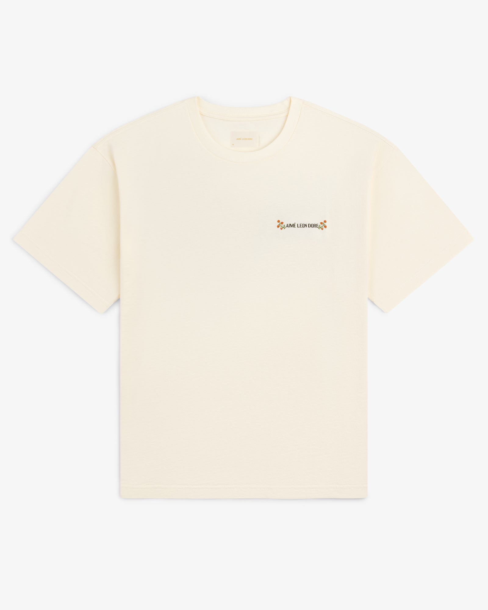 Aimé Postcard Tee: off-white short-sleeve shirt with small floral graphic and text on the left chest.