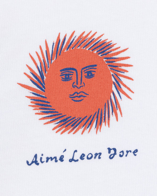 The Fassianos "Sovereign Sun" Tee features an orange sun face with blue rays above handwritten Aimé Leon Dore text.