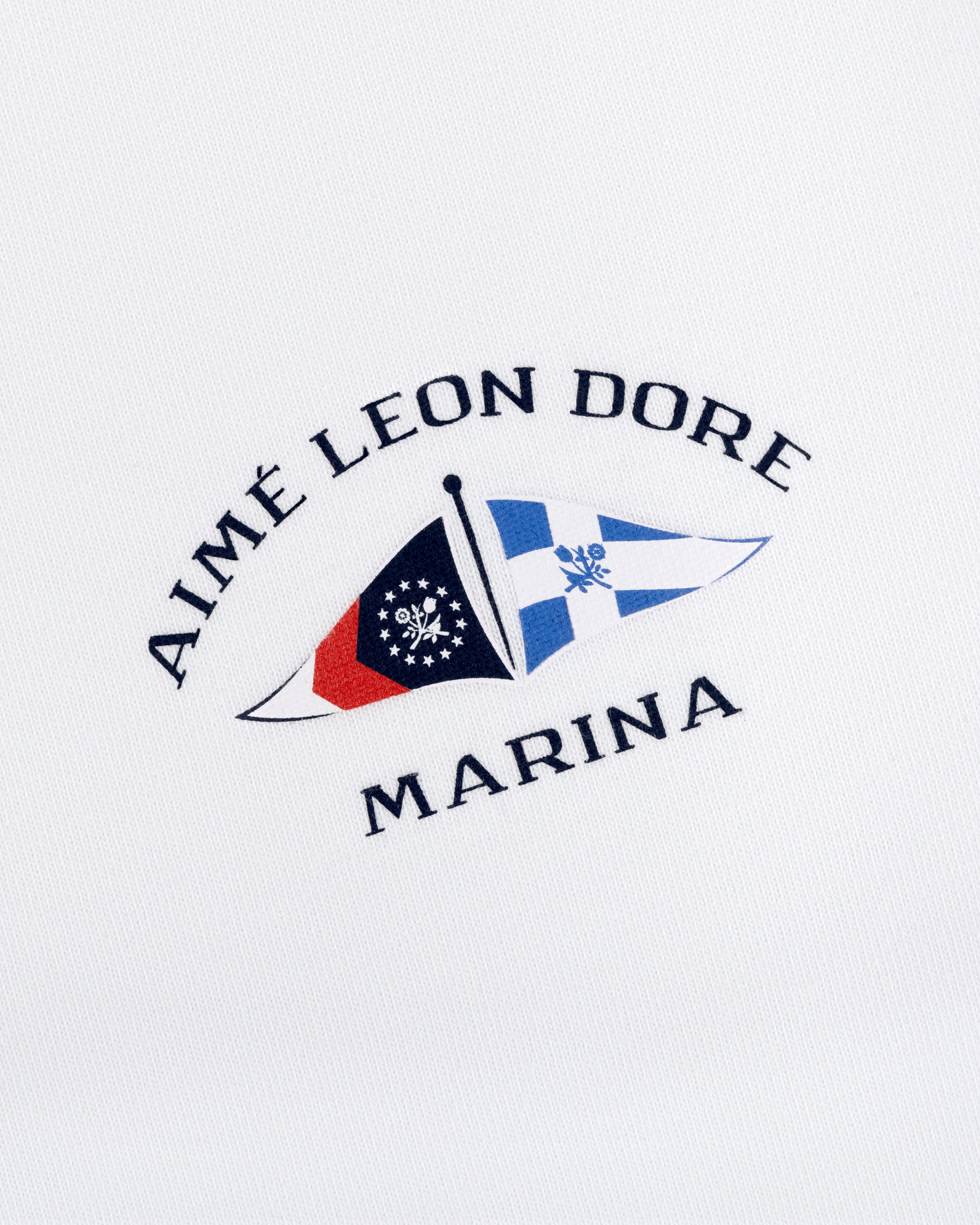 Marina Tee featuring embroidered Aimé Leon Dore Marina logo with two nautical flags on a white background.