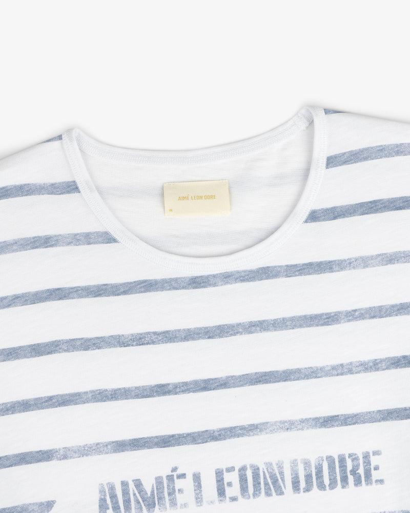 Slub Beach Tee: White tee with faded blue horizontal stripes and visible AIMÉ LEON DORE label inside the collar.