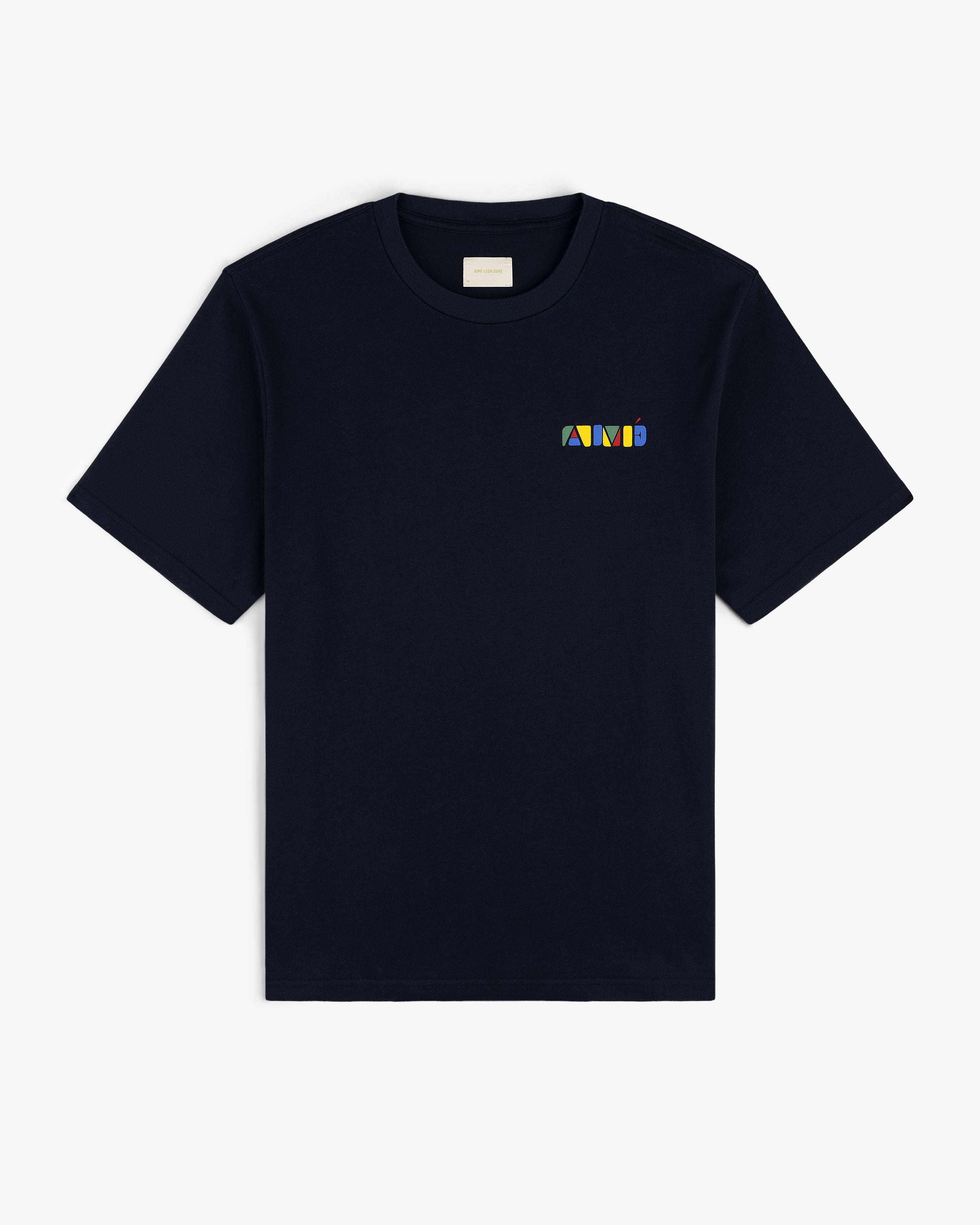 Stacked Logo Tee in black with a small, colorful geometric logo on the left chest, shown on white background.