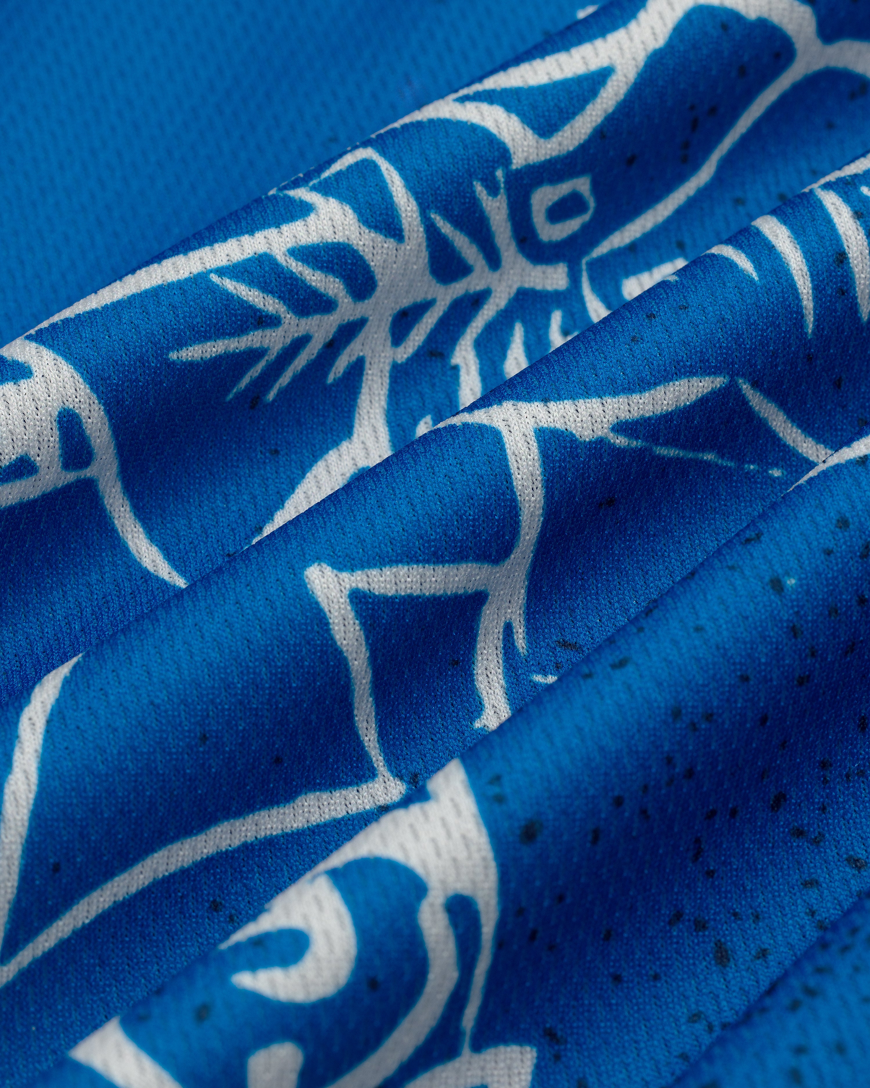Close-up of the Fassianos Half-Zip Cycling Jersey's blue fabric with white abstract animal designs and visible stitching.