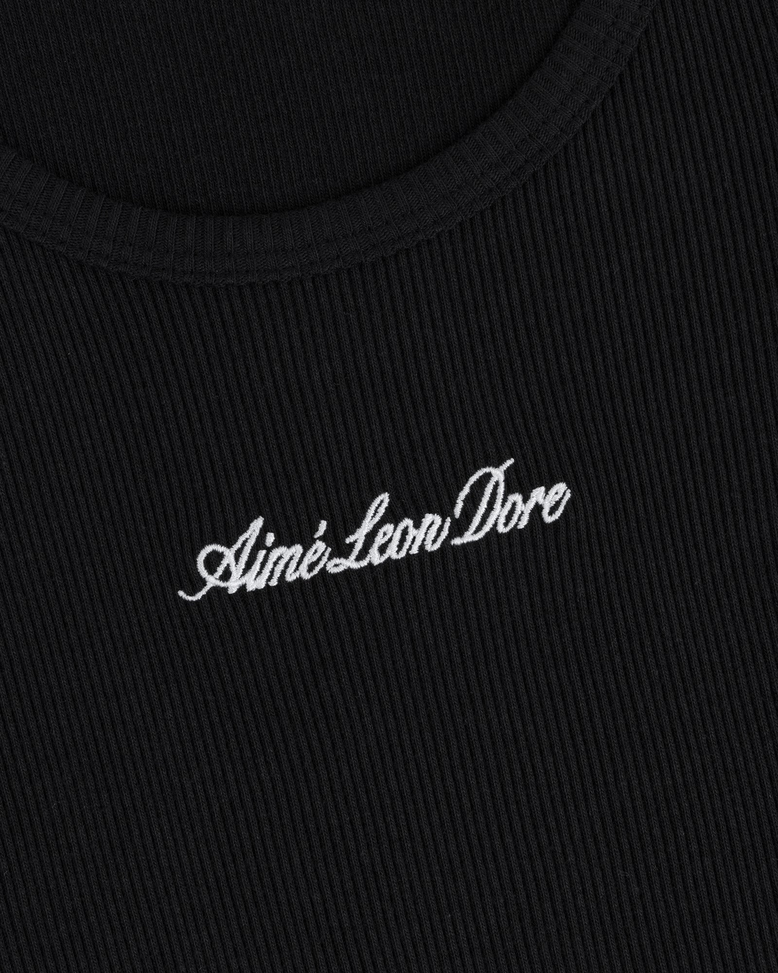 Close-up of black ribbed Embroidered Logo Tank Top with “Aimé Leon Dore” in white cursive embroidery.