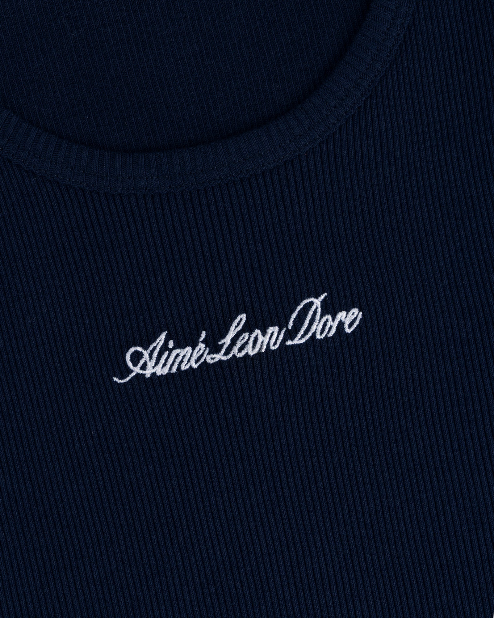 Close-up of navy ribbed fabric on the Embroidered Logo Tank Top with Aimé Leon Dore in white cursive.
