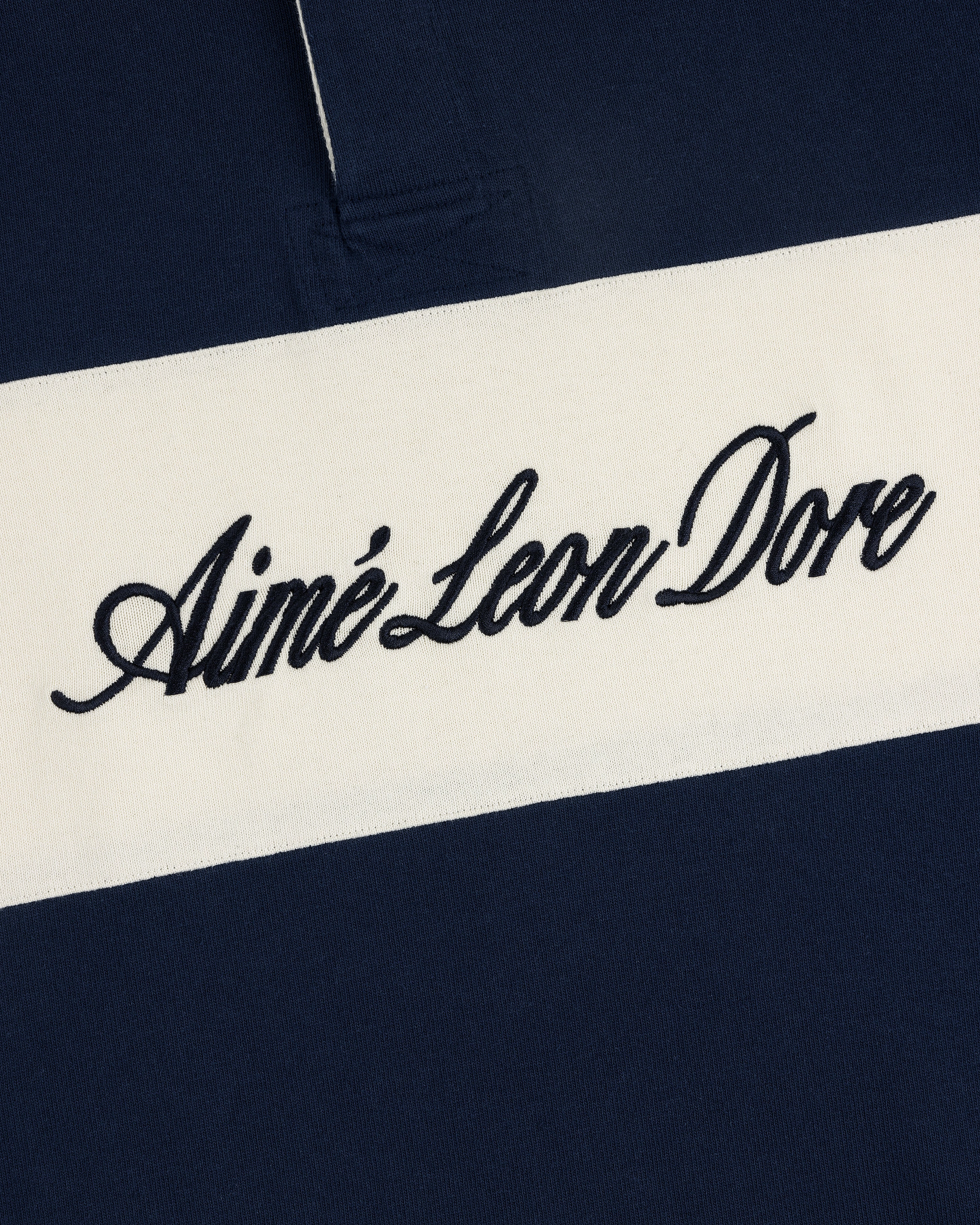 Navy Script Paneled Rugby with a white horizontal stripe and black cursive Aimé Leon Dore embroidery.