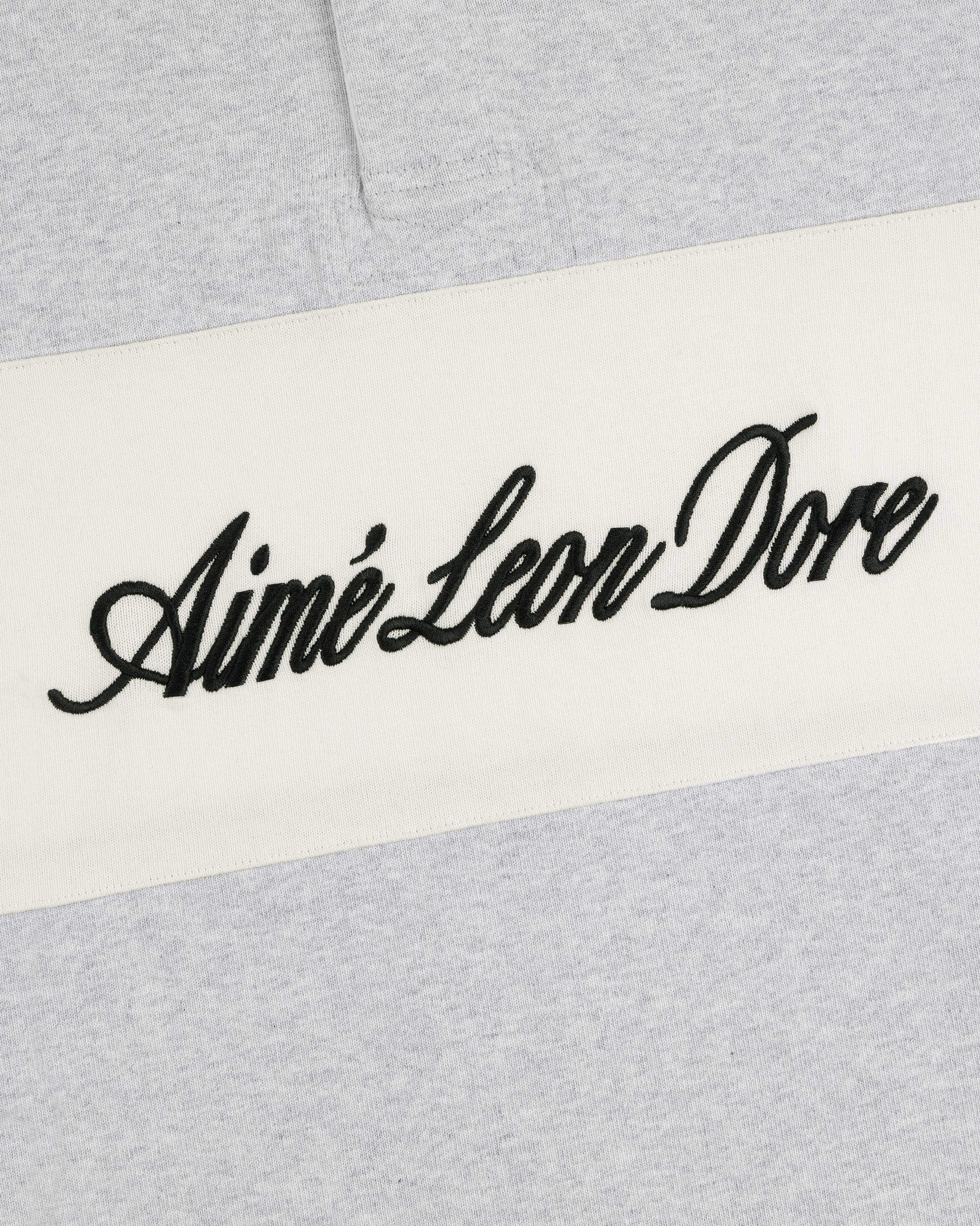 Close-up of a light gray Script Paneled Rugby with black Aimé Leon Dore script on a white horizontal stripe.