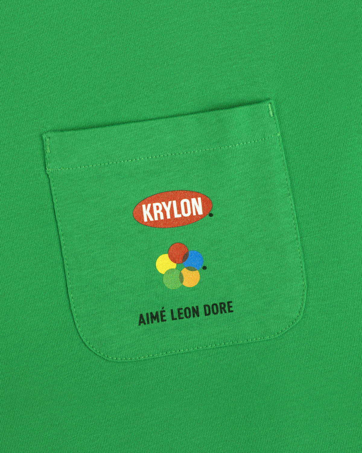 Krylon Pocket Tee: Green shirt with KRYLON logo, colorful paint splatters, and AIMÉ LEON DORE text below.