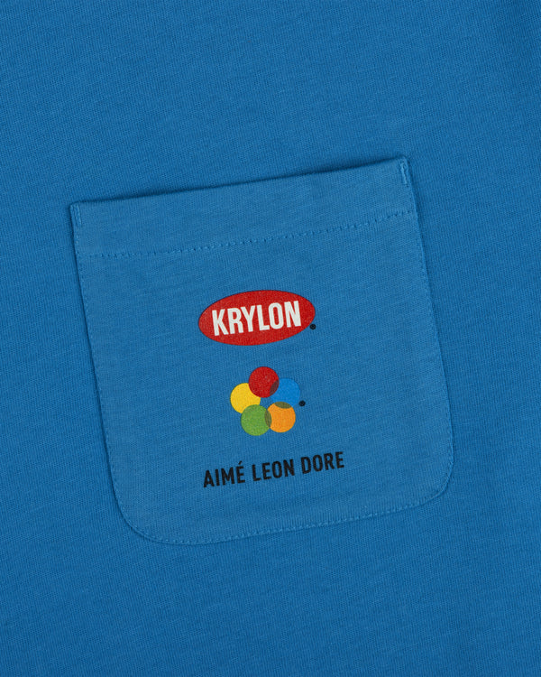 Krylon Pocket Tee features a blue pocket with four paint circles and AIMÉ LEON DORE printed on the front.