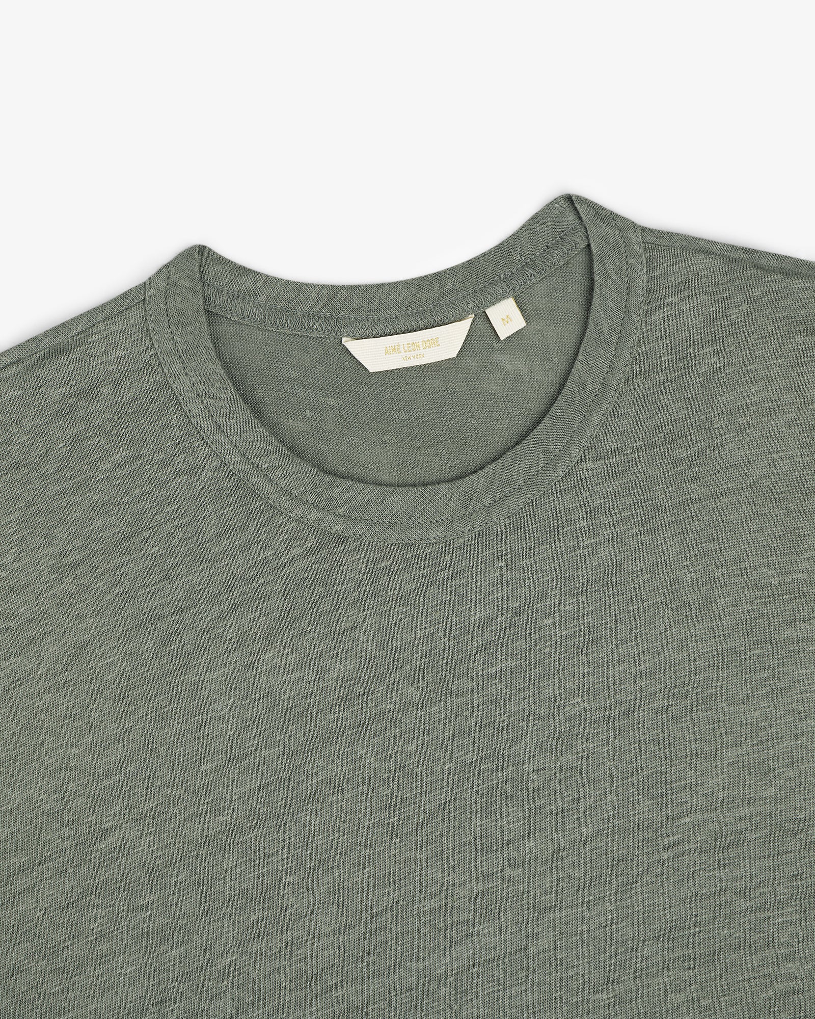Linen Tee in grayish-green, crew neck style, laid flat to display the collar and inner label.